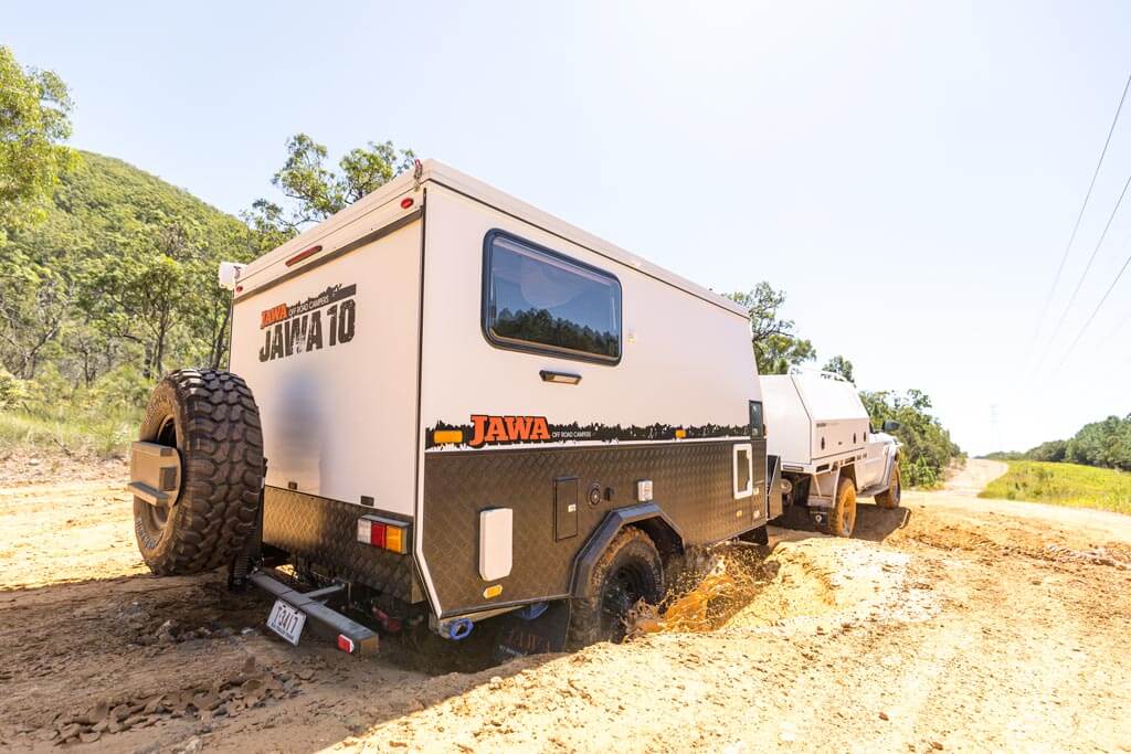 The Jawa Trax 10 Hybrid Camper Trailer going through some mud and making a splash