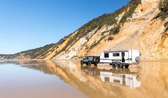 4wd and caravan on the beach with reflections of coloured sands